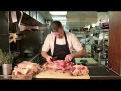 a man in an apron cuts up meat on a cutting board