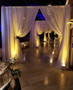 an indoor wedding venue with white drapes and candles