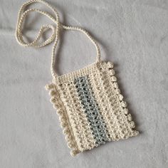 a crocheted bag is laying on a white surface with a string attached to it