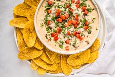 a white bowl filled with dip surrounded by tortilla chips