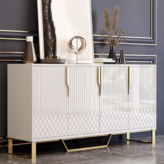 a white and gold sideboard in a room with art on the wall behind it