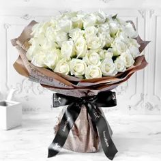 a bouquet of white roses wrapped in brown paper