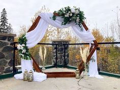 an outdoor wedding setup with white flowers and greenery on the top of a stone structure