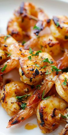 grilled shrimp on a white plate with garnishes and lime wedges