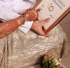 the bride and groom are holding their hands together in front of a framed wedding card