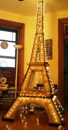 the eiffel tower is lit up with christmas lights in front of a window