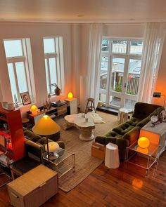 a living room filled with lots of furniture next to large windows on top of a hard wood floor