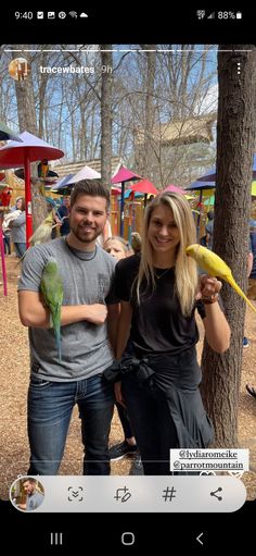 two people standing next to each other with birds on their hands and one holding a banana