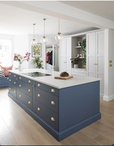 a large kitchen with blue cabinets and white counter tops