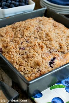 a blueberry crumb cake in a pan on a table with plates and napkins