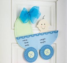 a door hanger with a baby's carriage on it and a blue bow