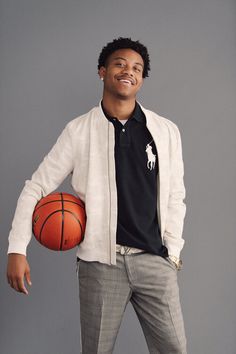 a young man holding a basketball in his right hand and posing for the camera,