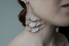 a close up of a woman's neck with white paint on it