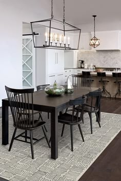 a dining room table with four chairs and a chandelier hanging from the ceiling