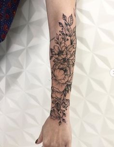 a woman's arm with flowers and leaves tattooed on the left side of her arm