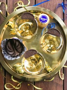 an assortment of desserts on a gold plate with blue and white ribbons around it