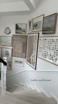 a staircase with pictures on the wall above it and below is a handrail that leads up to an upstairs landing