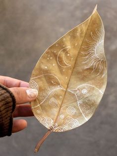 a person holding a leaf with designs on it