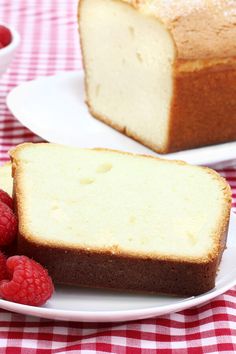 two plates with bread and raspberries on a red checkered picnic tablecloth