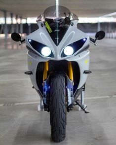 a white motorcycle parked in a parking lot with lights on it's headlight