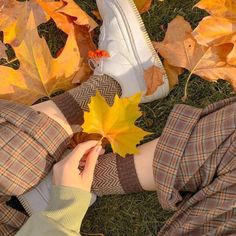 a person laying on the ground with a leaf in their hand and shoes next to them