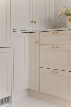 a white kitchen with marble counter tops and gold pulls on the cabinet door knobs