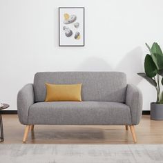 a grey couch sitting next to a table on top of a hard wood floored floor