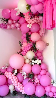 pink and white balloons are hanging from the ceiling