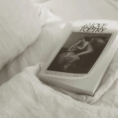 an open book sitting on top of a bed next to white sheets and pillow covers