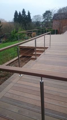 a wooden deck with railings and steps leading up to the grass area behind it