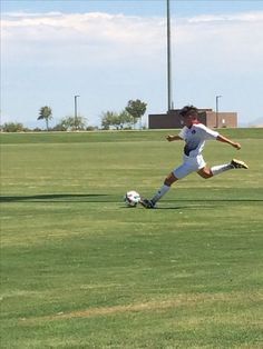 a young man kicking a soccer ball across a field