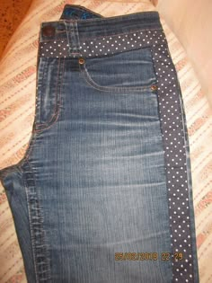 a pair of blue jeans with polka dots on them are sitting on a bed next to a pillow