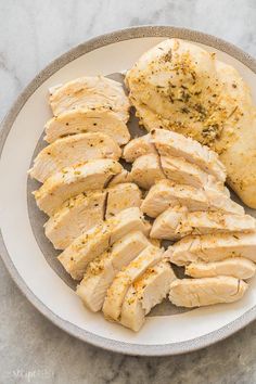 sliced chicken on a plate with seasoning sprinkled around it and another piece of meat in the background