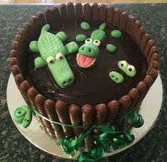 a chocolate cake decorated with green decorations and alligators on it's face, sitting on a table