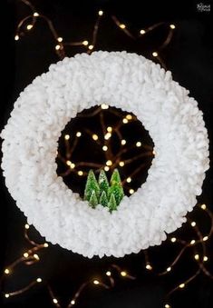 a knitted wreath with small trees on it and lights in the backround