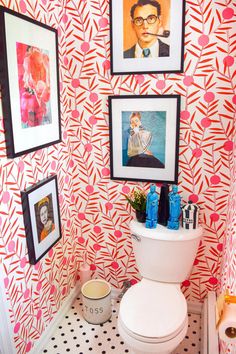 a white toilet sitting in a bathroom next to pictures on the wall and a sink