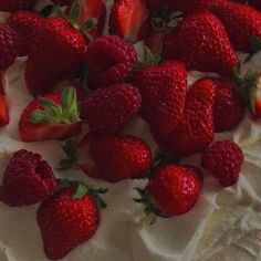 a cake with white frosting and strawberries on top is surrounded by other strawberry's