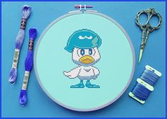 a cross stitch pattern with scissors and thread on a blue background, next to it is an embroidery kit