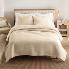 the bed is made up with beige linens and pillows, along with two side tables