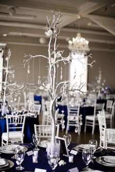 the centerpieces are decorated with silver and white flowers, branches, and pearls