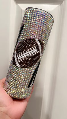 a hand holding up a phone case that has a football on it and is decorated with sequins