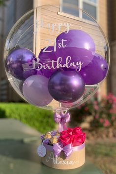 purple balloons are in a clear vase with a happy 1st birthday message on it,