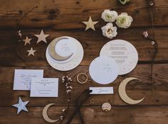 the wedding stationery is laid out on top of the wooden table with flowers and stars