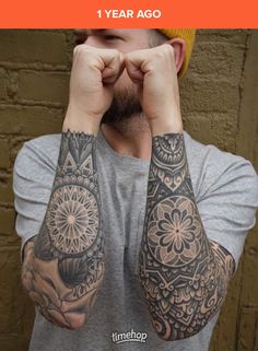 a man with tattoos on his arms covering his eyes