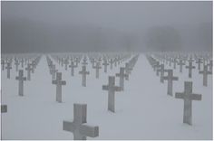 many crosses are covered in snow on a cold winter's day at the cemetary