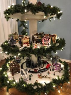 a christmas tree with lights and toys on the bottom shelf in front of a window