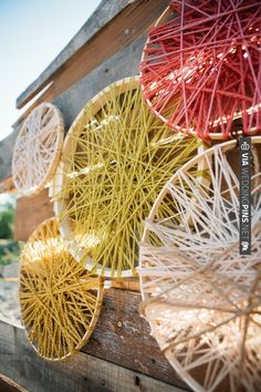 colorful string art hanging from the side of a wooden structure with red and yellow strings attached to it