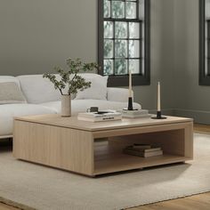 a living room with a white couch, coffee table and window in the back ground