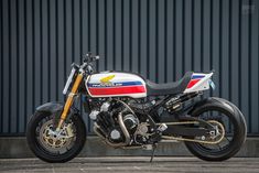 a red, white and blue motorcycle parked in front of a building