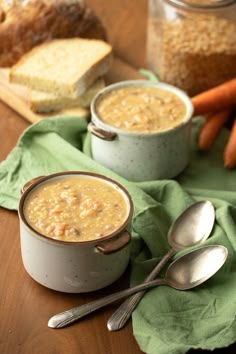 two bowls filled with soup next to carrots and bread